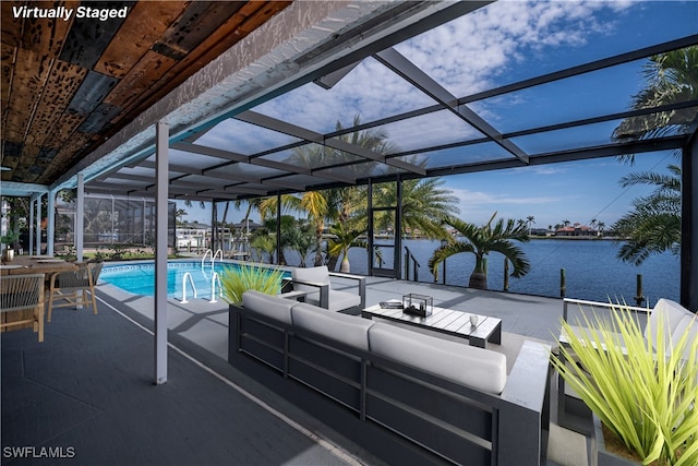 pool featuring glass enclosure, outdoor lounge area, a patio, and a water view