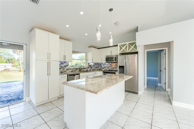 kitchen featuring sink, hanging light fixtures, stainless steel appliances, a kitchen island, and white cabinets