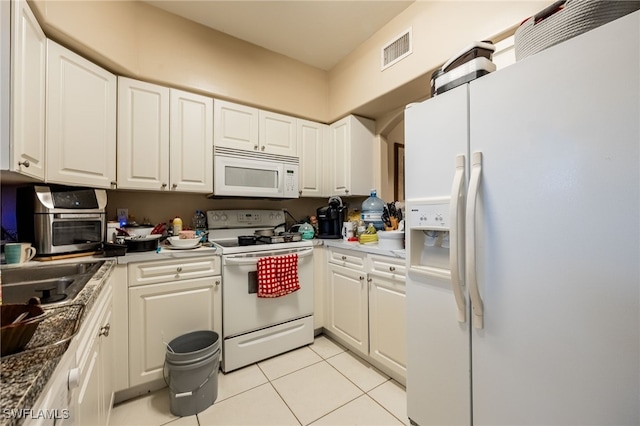 kitchen with light tile patterned floors, white appliances, and white cabinetry