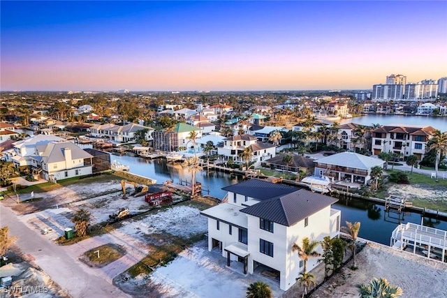aerial view at dusk featuring a residential view and a water view