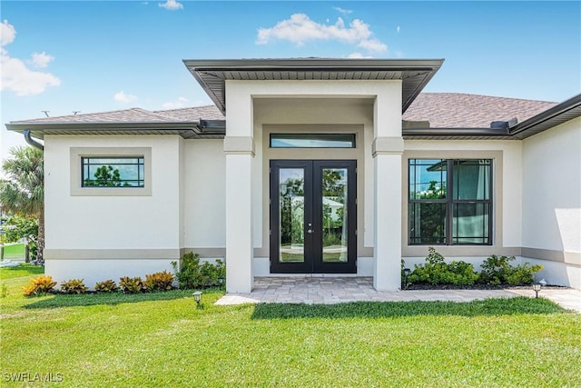 view of exterior entry featuring french doors and a lawn