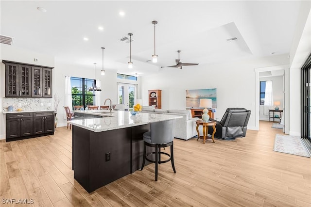 kitchen with a kitchen bar, dark brown cabinets, a large island, and sink