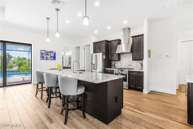 kitchen with a spacious island, hanging light fixtures, a breakfast bar area, wall chimney exhaust hood, and stainless steel appliances