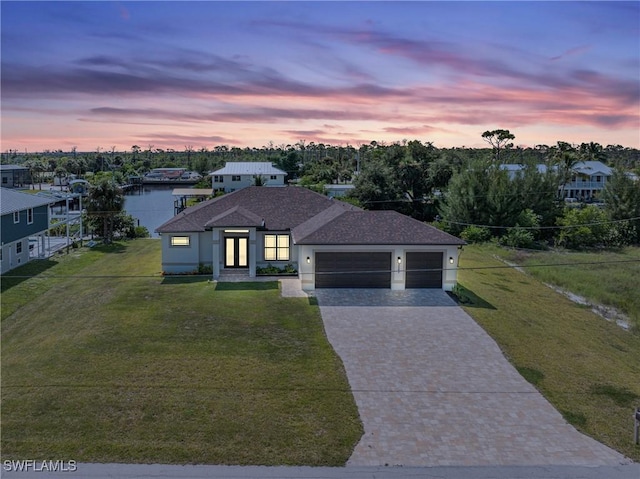 view of front of house featuring a yard, a water view, and a garage