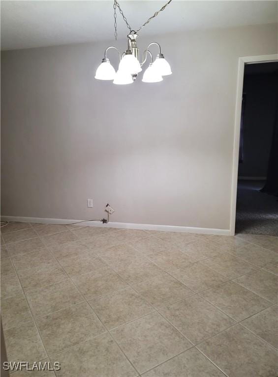 tiled spare room featuring an inviting chandelier