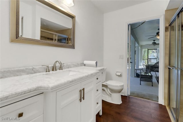 bathroom with ceiling fan, hardwood / wood-style floors, toilet, vanity, and a shower with shower door