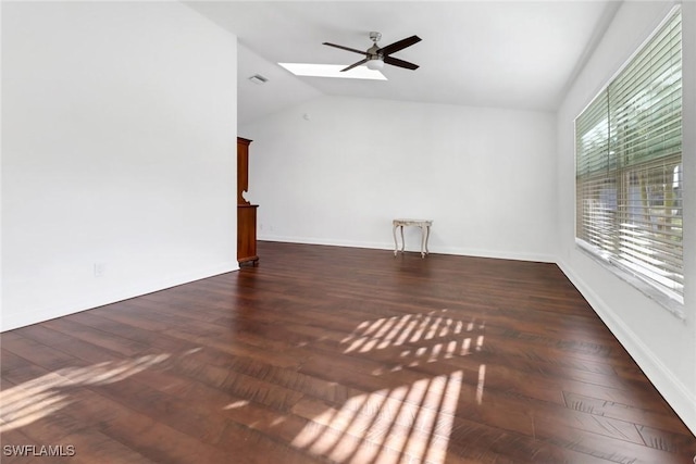 unfurnished room featuring lofted ceiling with skylight, ceiling fan, and dark hardwood / wood-style floors