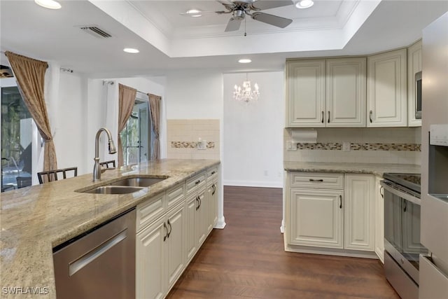 kitchen featuring light stone countertops, appliances with stainless steel finishes, a tray ceiling, and sink