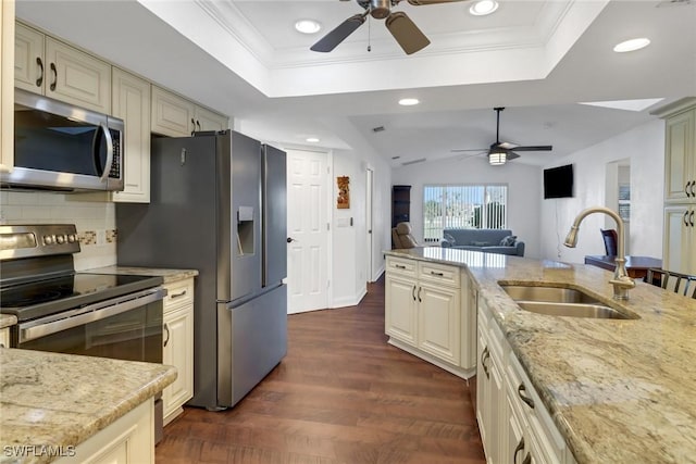 kitchen with light stone countertops, sink, cream cabinetry, and appliances with stainless steel finishes