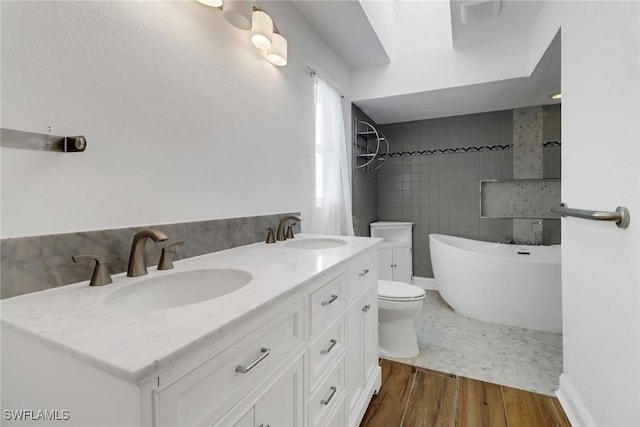 bathroom featuring toilet, vanity, a bath, and hardwood / wood-style flooring