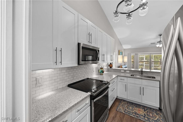 kitchen with appliances with stainless steel finishes, backsplash, sink, white cabinetry, and lofted ceiling