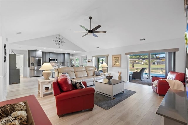 living room featuring ceiling fan with notable chandelier, light wood-type flooring, and lofted ceiling