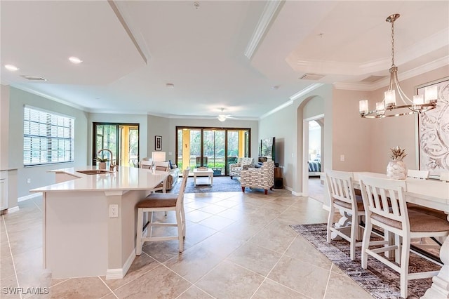 kitchen with pendant lighting, a kitchen island with sink, a kitchen breakfast bar, ceiling fan with notable chandelier, and sink