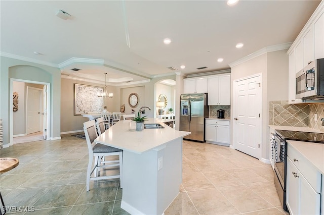 kitchen with a kitchen island with sink, white cabinets, sink, tasteful backsplash, and stainless steel appliances