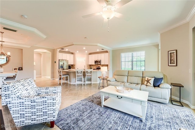 tiled living room featuring crown molding and ceiling fan with notable chandelier