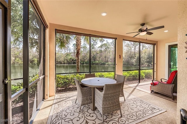 sunroom / solarium featuring ceiling fan and a water view