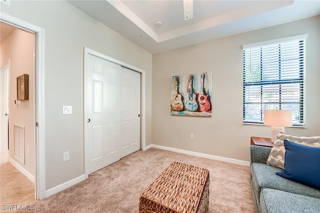 living area with a tray ceiling and light carpet