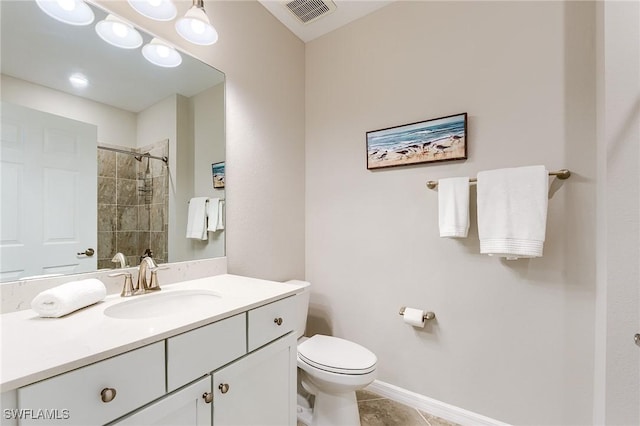 bathroom featuring tile patterned flooring, vanity, toilet, and tiled shower