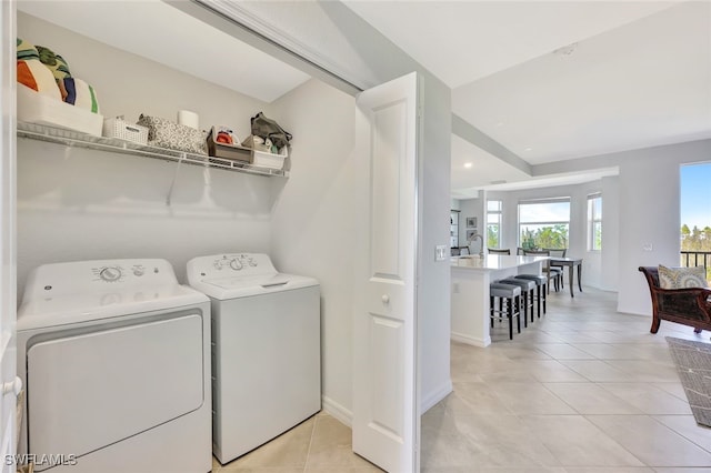 laundry area featuring separate washer and dryer, sink, and light tile patterned floors