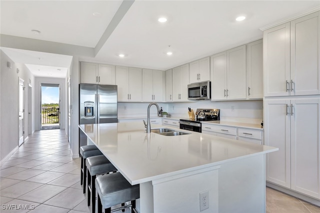 kitchen with white cabinets, a kitchen breakfast bar, sink, an island with sink, and appliances with stainless steel finishes