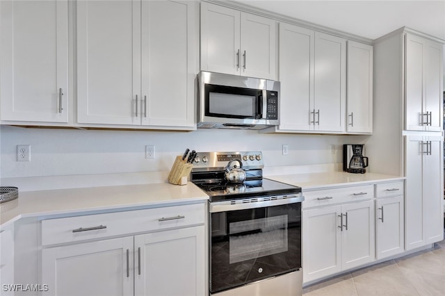 kitchen featuring appliances with stainless steel finishes, light tile patterned floors, and white cabinetry