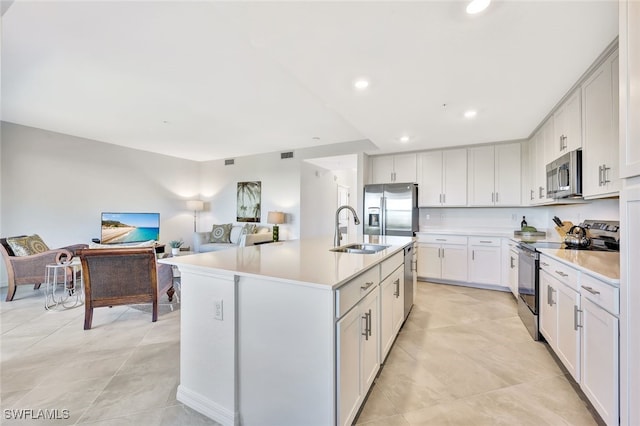 kitchen featuring white cabinets, stainless steel appliances, a kitchen island with sink, and sink