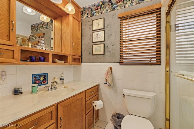 bathroom with vanity, toilet, a shower with shower door, and tile walls