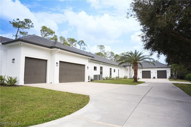 view of front of home with cooling unit, a garage, and a front lawn