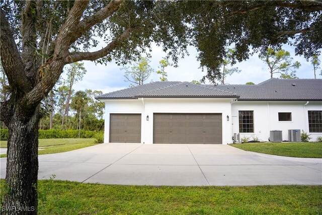 view of side of home featuring central air condition unit, a yard, and a garage