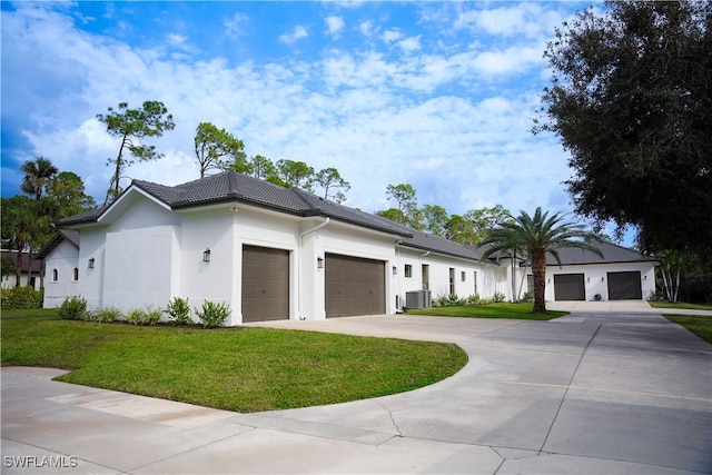 view of front of property with central AC unit, a garage, and a front lawn