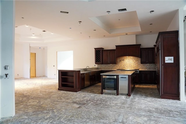 kitchen featuring dark brown cabinetry, tasteful backsplash, stainless steel dishwasher, a tray ceiling, and a kitchen island