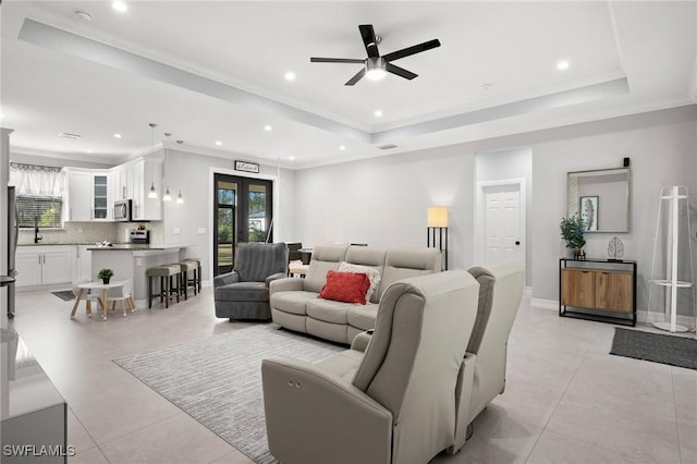 living room with ceiling fan, a raised ceiling, crown molding, and french doors