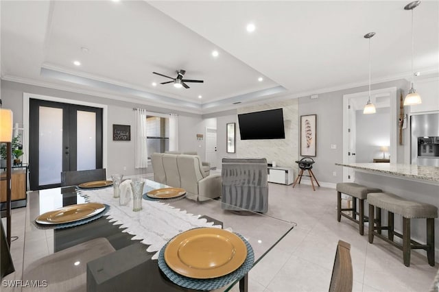 tiled living room with a tray ceiling, ceiling fan, and ornamental molding