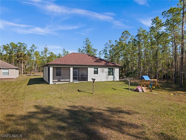 back of house featuring a playground and a lawn