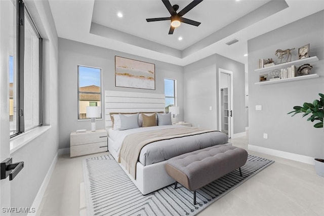 bedroom featuring a raised ceiling, multiple windows, and ceiling fan