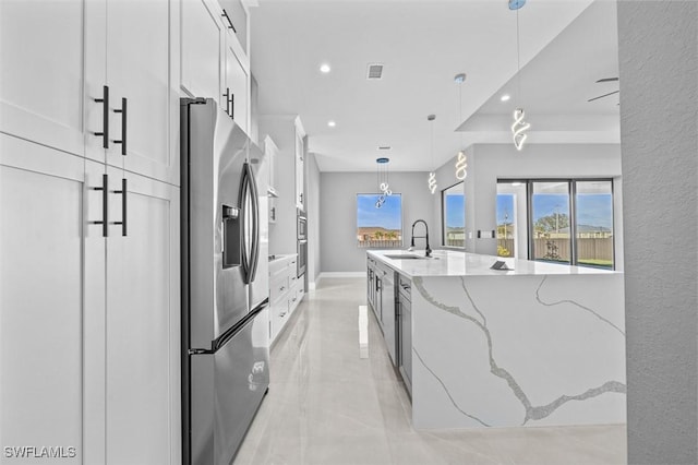 kitchen with pendant lighting, sink, light stone counters, white cabinetry, and stainless steel appliances