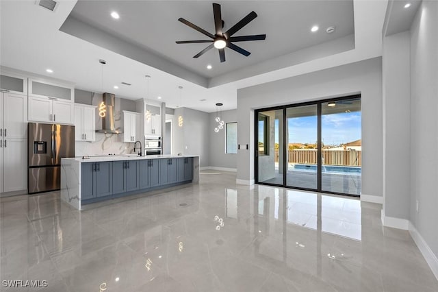 kitchen with pendant lighting, white cabinetry, stainless steel fridge with ice dispenser, and wall chimney range hood