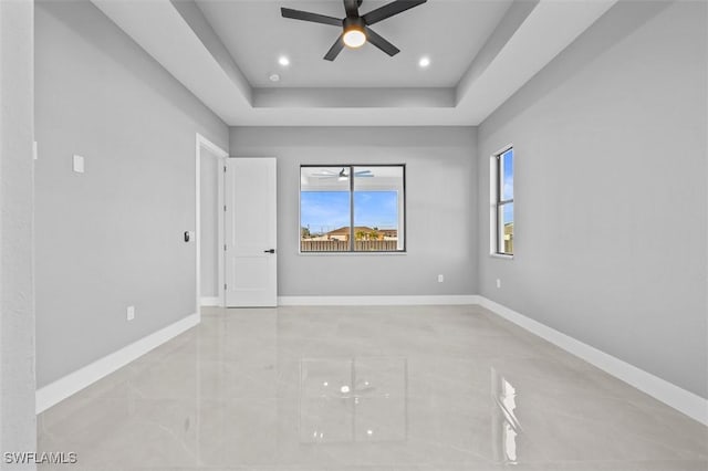 spare room featuring a tray ceiling and ceiling fan