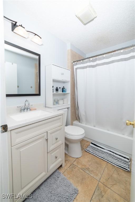 full bathroom with a textured ceiling, vanity, shower / bath combo, and toilet