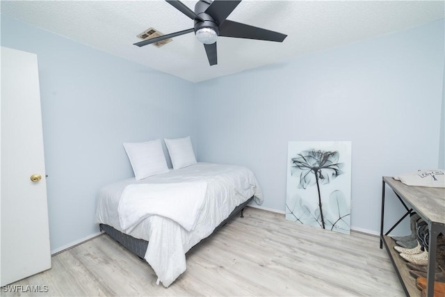 bedroom with ceiling fan, a textured ceiling, and light wood-type flooring