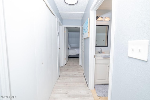 corridor featuring light hardwood / wood-style flooring, a textured ceiling, and sink