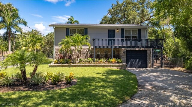 27311 S Riverside Dr, Bonita Springs, FL 34135 - view of front of house with stone siding, driveway, a front lawn, and an attached garage