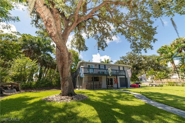 back of property with a garage, a wooden deck, and a lawn