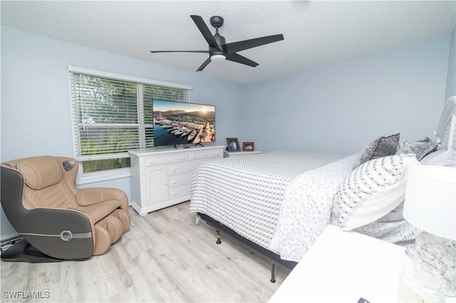 bedroom with ceiling fan, a textured ceiling, and light hardwood / wood-style flooring