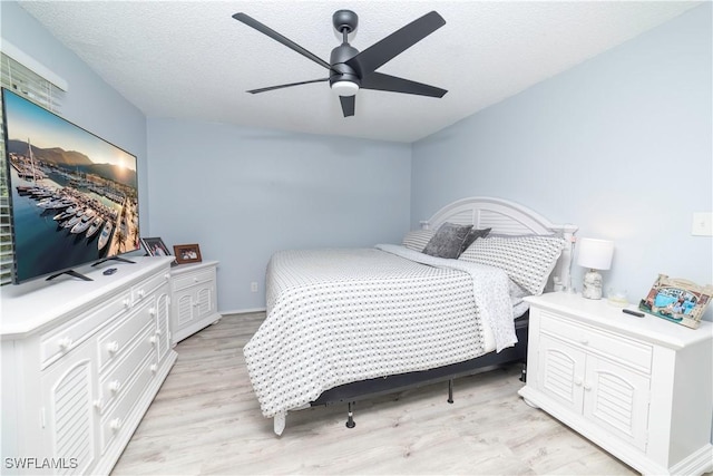 bedroom with a textured ceiling, light hardwood / wood-style flooring, and ceiling fan