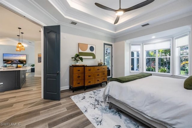 bedroom with ceiling fan, hardwood / wood-style floors, ornamental molding, and a raised ceiling