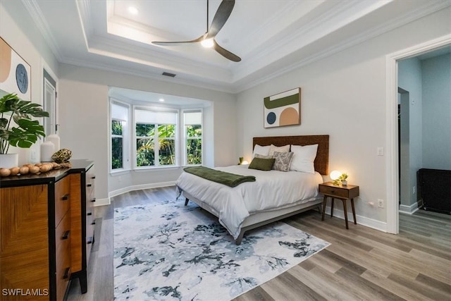 bedroom featuring ceiling fan, crown molding, a raised ceiling, and hardwood / wood-style floors