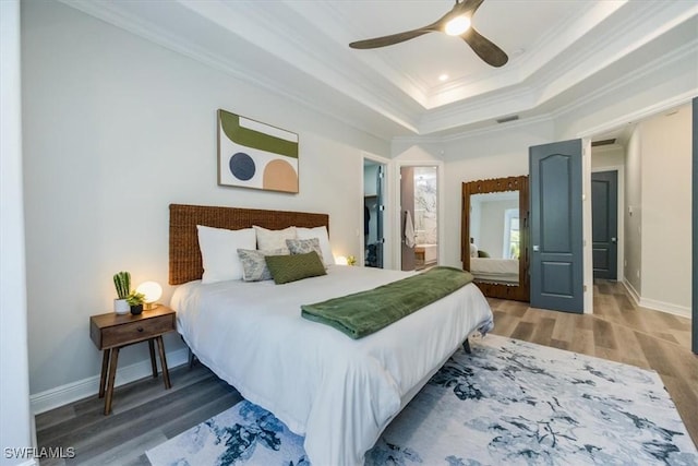 bedroom featuring ceiling fan, crown molding, ensuite bath, and hardwood / wood-style floors