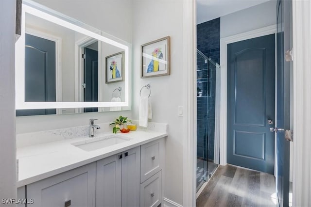 bathroom with wood-type flooring, a shower with door, and vanity