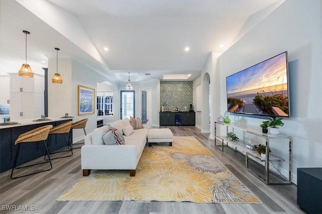 living room featuring light wood-type flooring, lofted ceiling, and ornamental molding